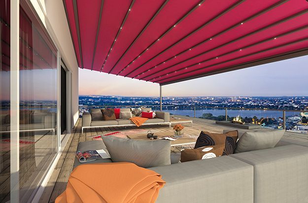 Eine Terrasse mit einer rosa Markise und Blick auf das Meer.