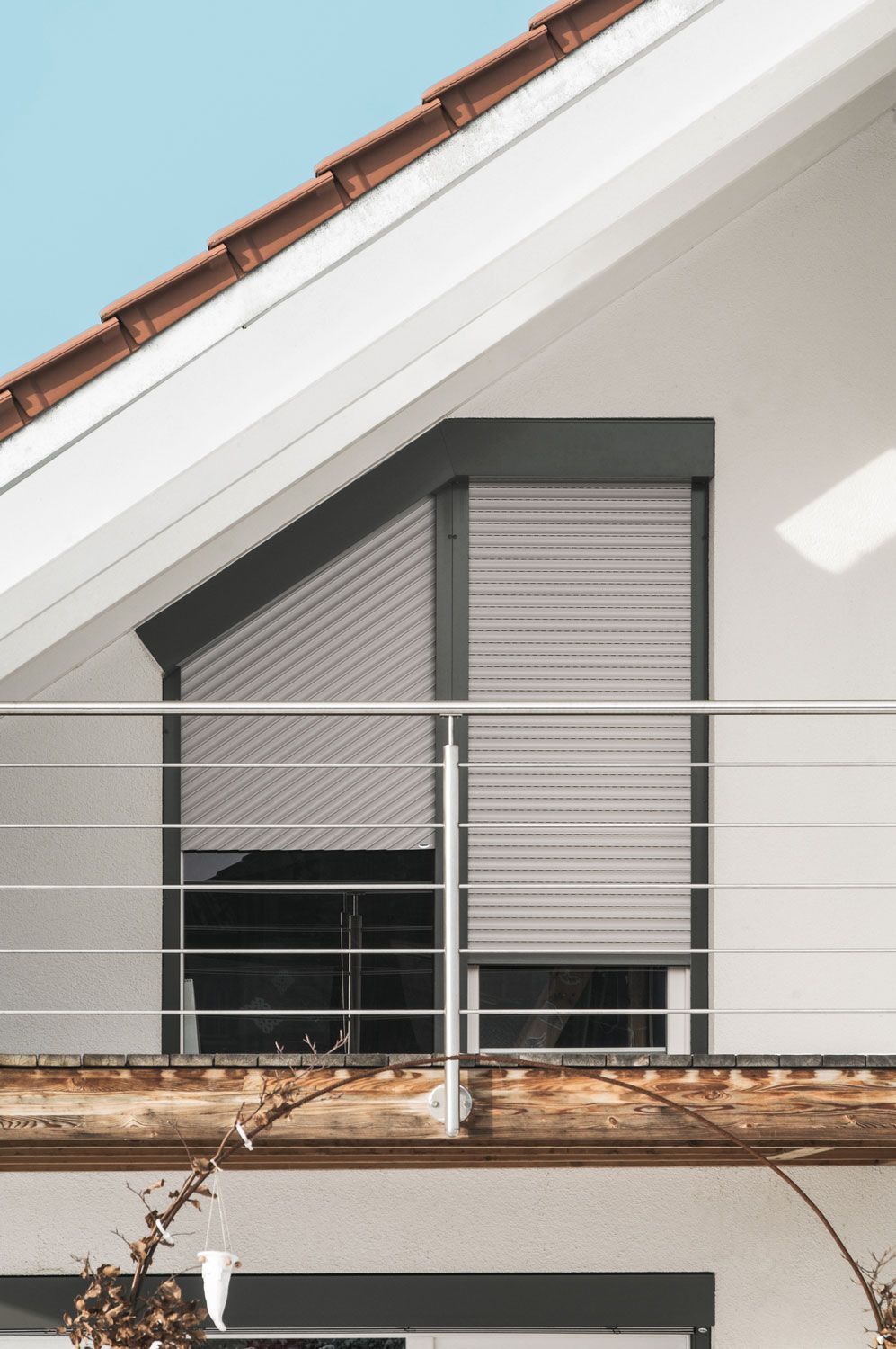 Ein Balkon mit Edelstahlgeländer und einem Fenster mit Rollläden.