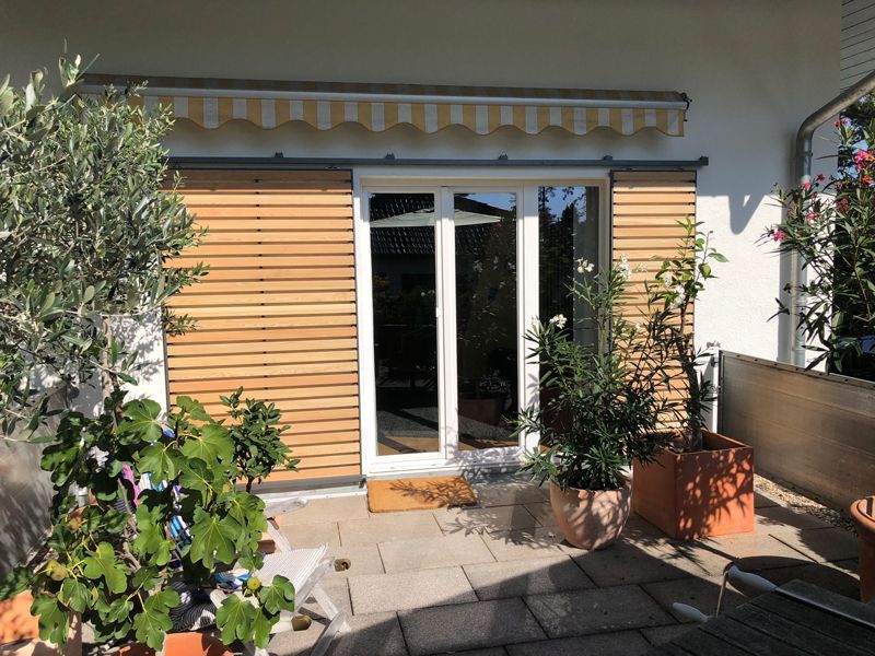 Eine Terrasse mit Topfpflanzen und einer Glasschiebetür.