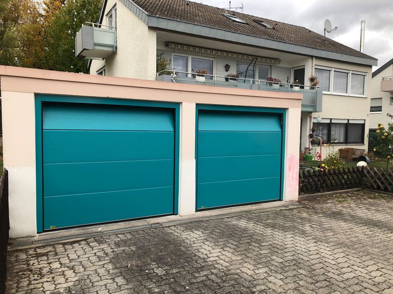 Ein Haus mit zwei blauen Garagentoren davor.