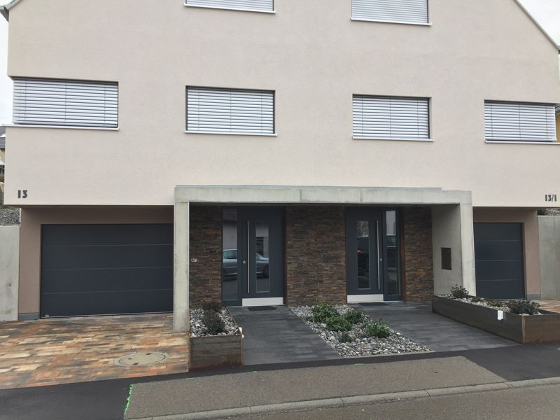 Ein Haus mit vielen Fenstern und einem schwarzen Garagentor