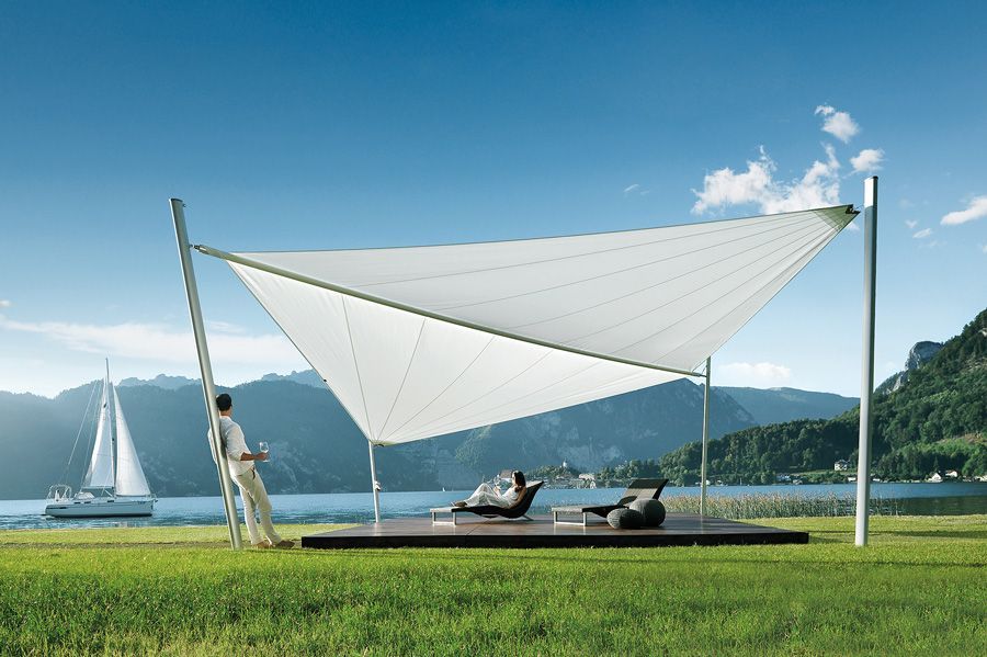 Ein Mann steht unter einem großen weißen Sonnenschirm und blickt auf einen See