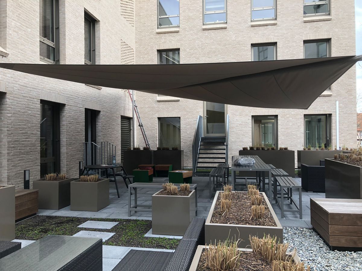 Eine Terrasse mit einem Tisch und Stühlen unter einem Sonnenschirm vor einem Gebäude.