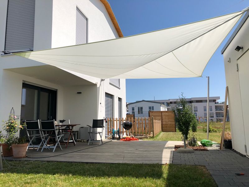 Ein weißes Haus mit einem weißen Segel, das die Terrasse überdacht.