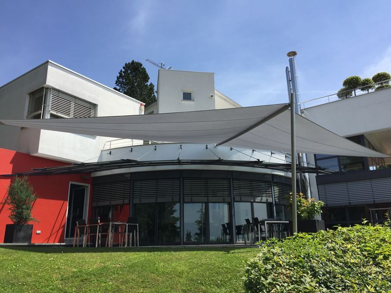 Ein großes weißes Gebäude mit einem großen weißen Sonnenschirm davor.