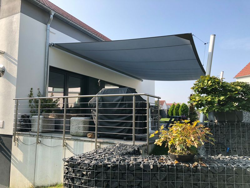 Eine große Markise überdacht den Balkon eines Hauses.