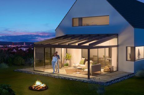 Ein Paar steht auf einer Terrasse vor einem Haus mit einer Feuerstelle.