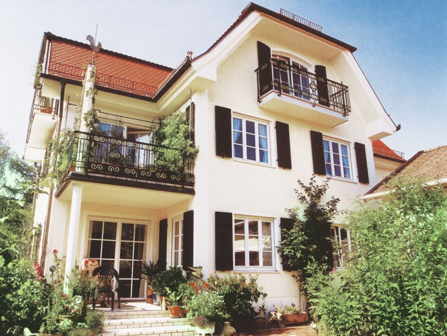 Ein weißes Haus mit schwarzen Fensterläden und einem Balkon