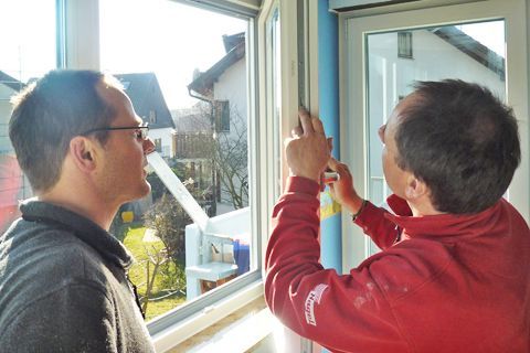 Zwei Männer arbeiten an einem Fenster in einem Haus.