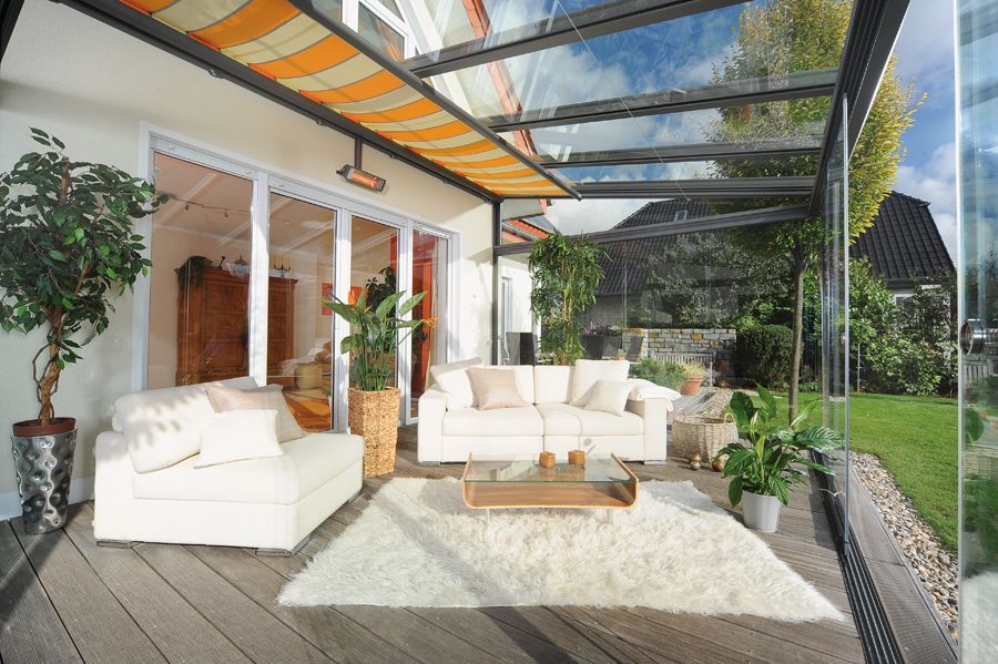 Ein Wohnzimmer mit Couch, Stühlen und Tisch unter einem Glasdach.