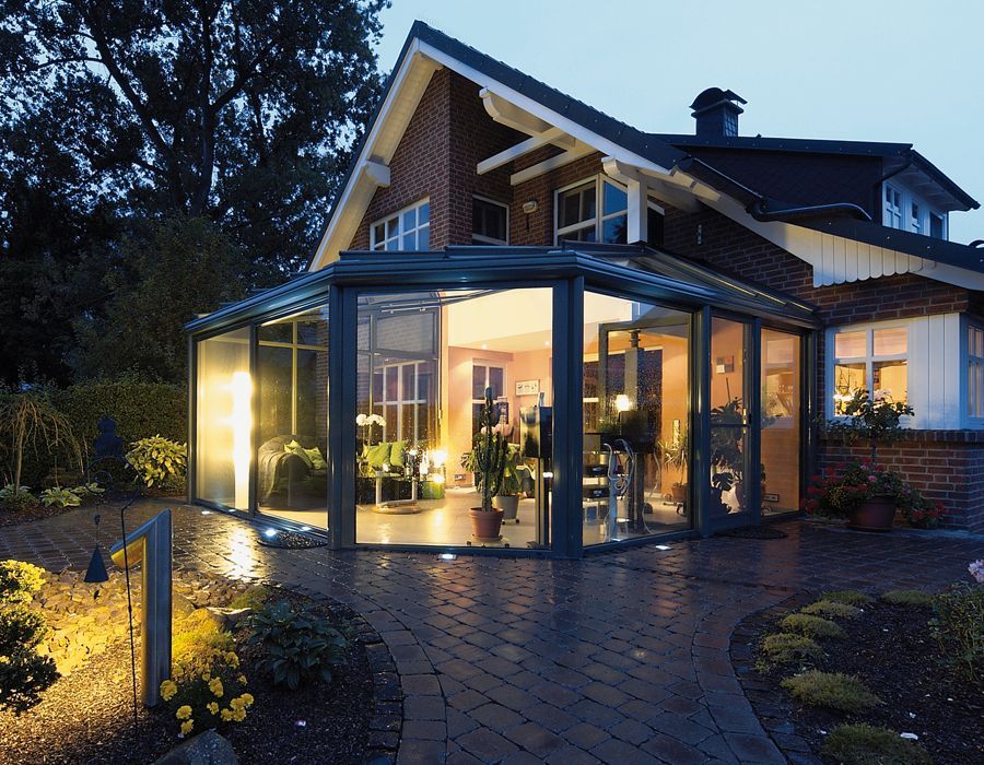 Ein Backsteinhaus mit einem großen Wintergarten aus Glas im Hinterhof