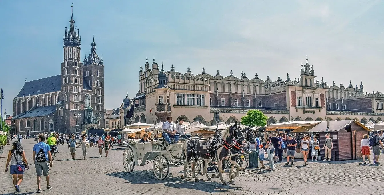 Powóz konny jedzie brukowaną ulicą przed kościołem.