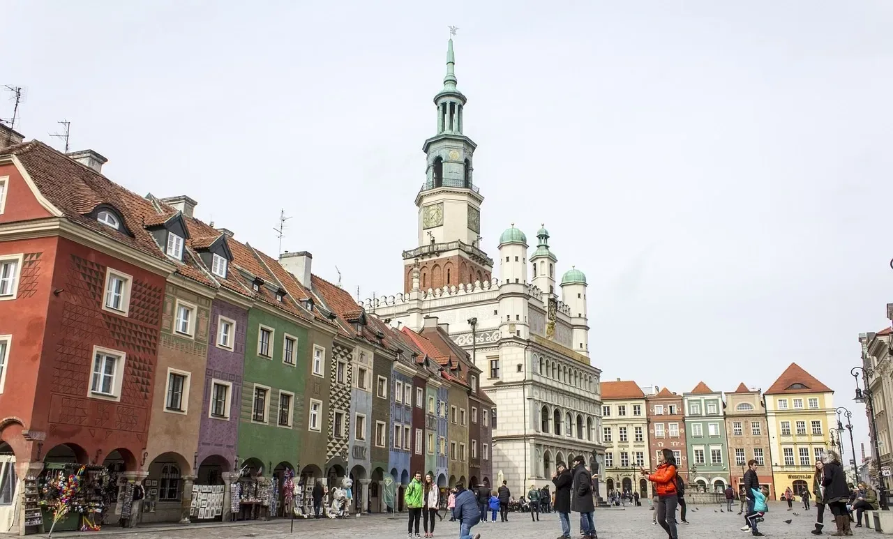 Grupa ludzi idzie przed dużym budynkiem.