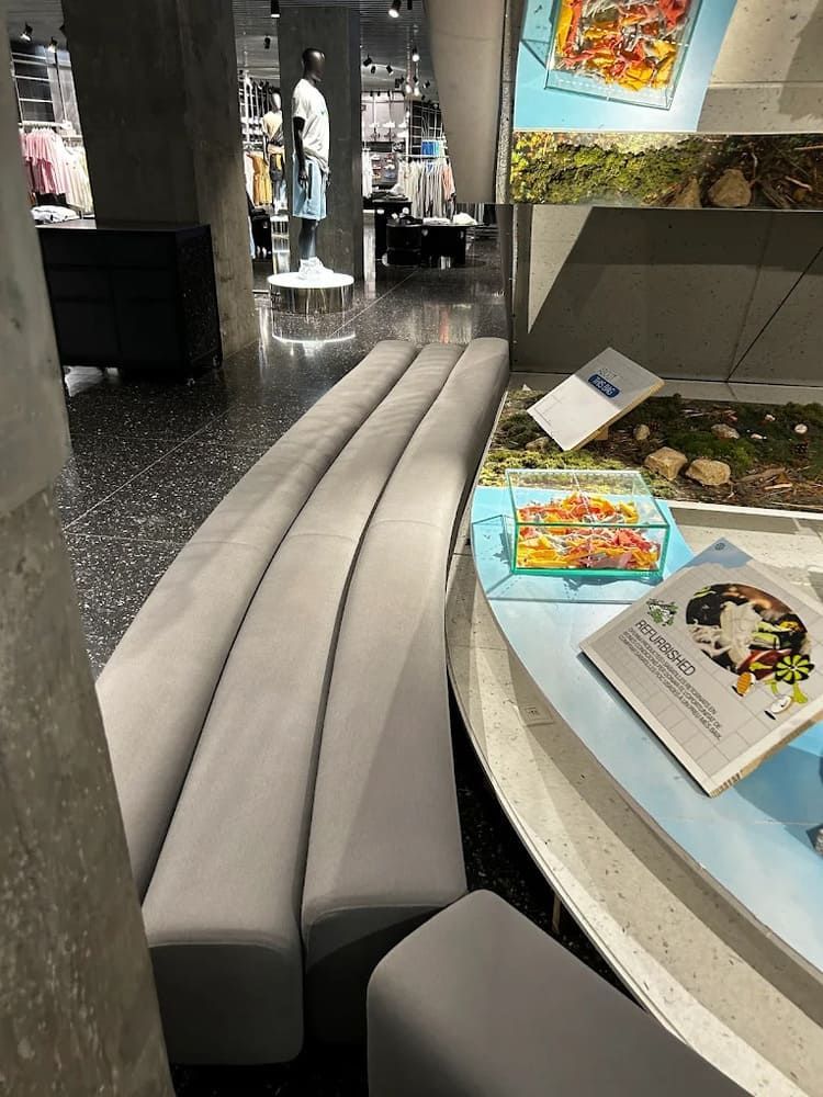 Banco gris largo y curvo en una tienda. Mesa de exposición con libros y obras de arte.