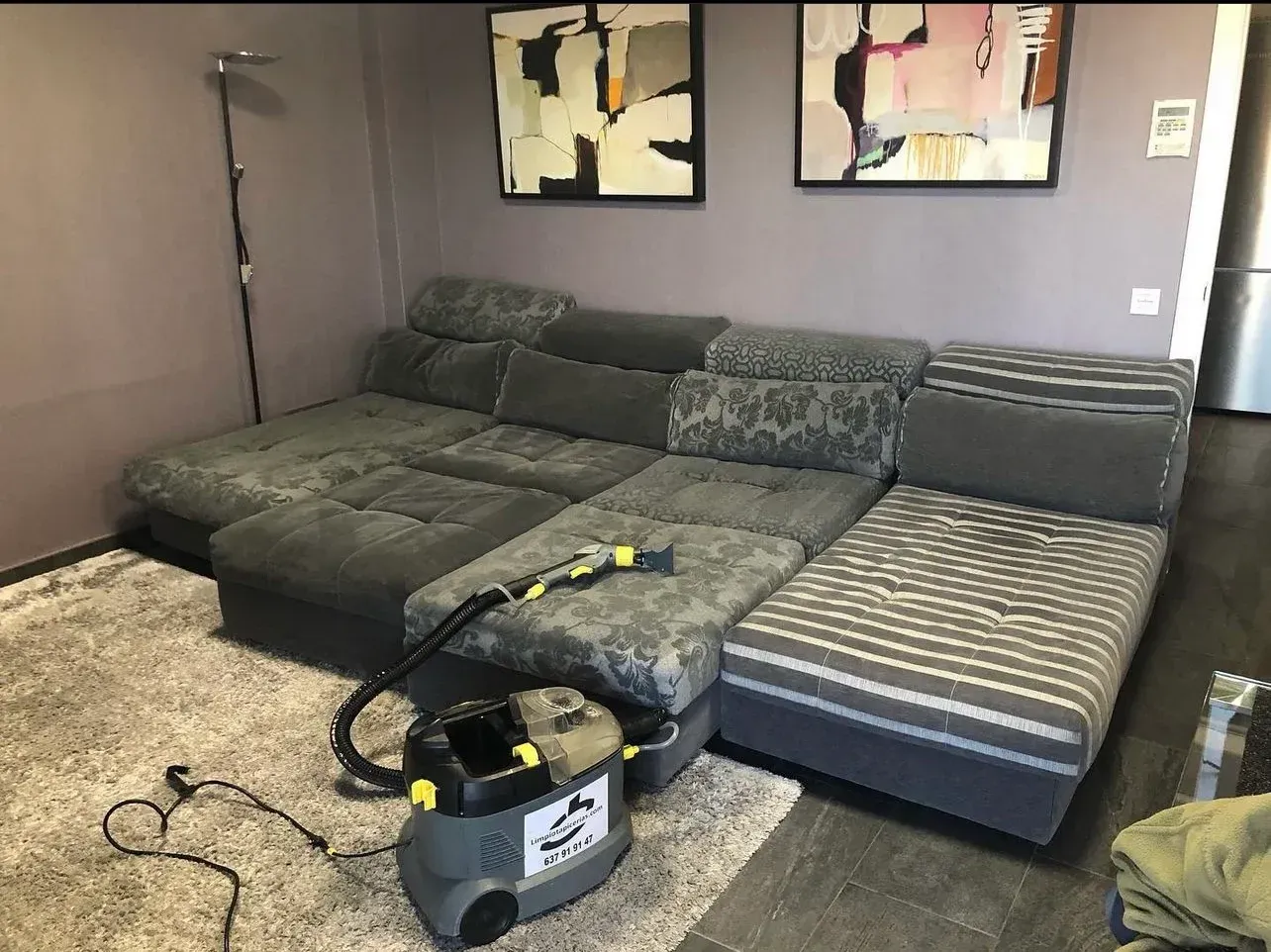 Un sofá seccional gris que se limpia con un limpiador de alfombras en una sala de estar.