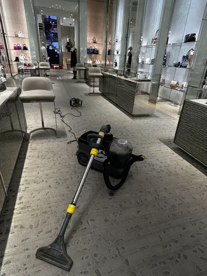 Una máquina de limpieza de alfombras descansa sobre la moqueta estampada en el pasillo de una tienda de lujo.