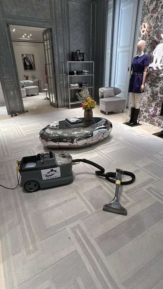 Una máquina limpiadora de alfombras en una tienda de lujo con una mesa ovalada central y maniquíes.