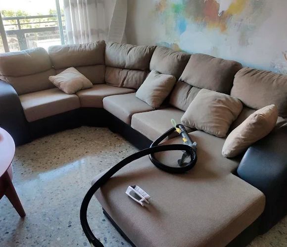 Sofá seccional marrón en forma de L con lados oscuros, almohadas y manguera de narguile.