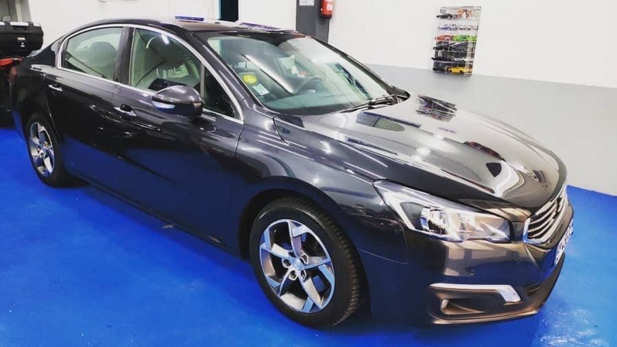 Un coche negro está aparcado en un suelo azul en un garaje.