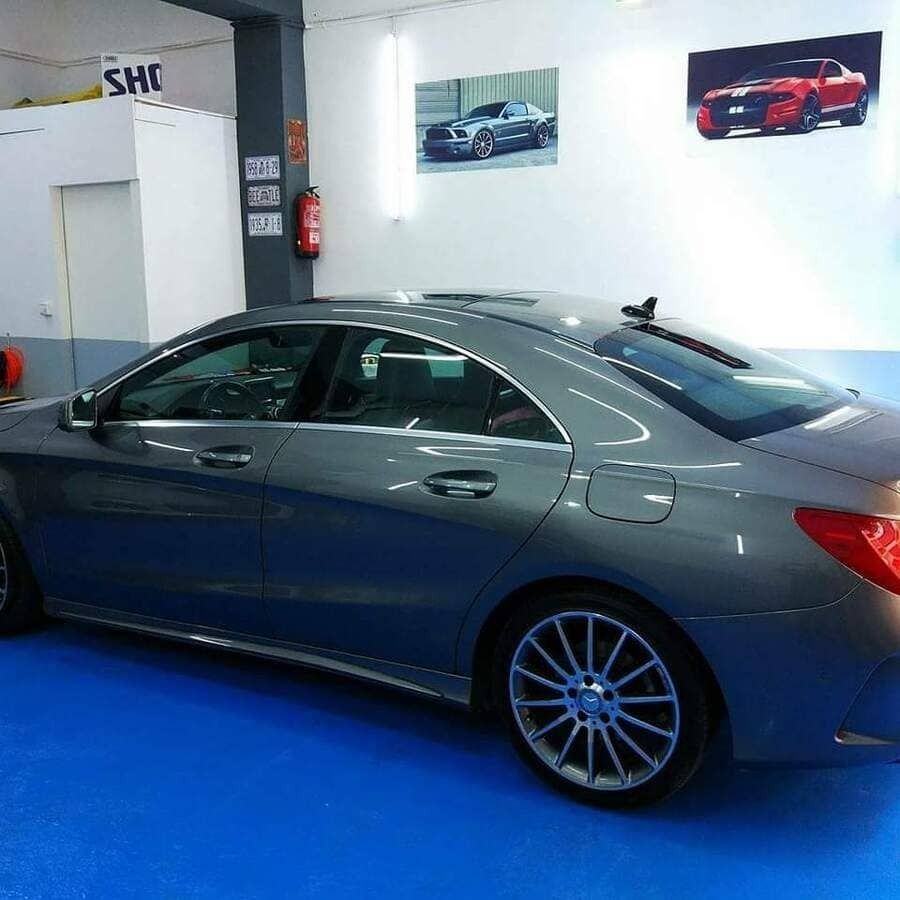 Un coche gris está aparcado en una habitación con un cartel que dice shc