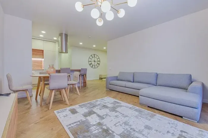 Una sala de estar con un sofá, sillas, una alfombra y un reloj en la pared.