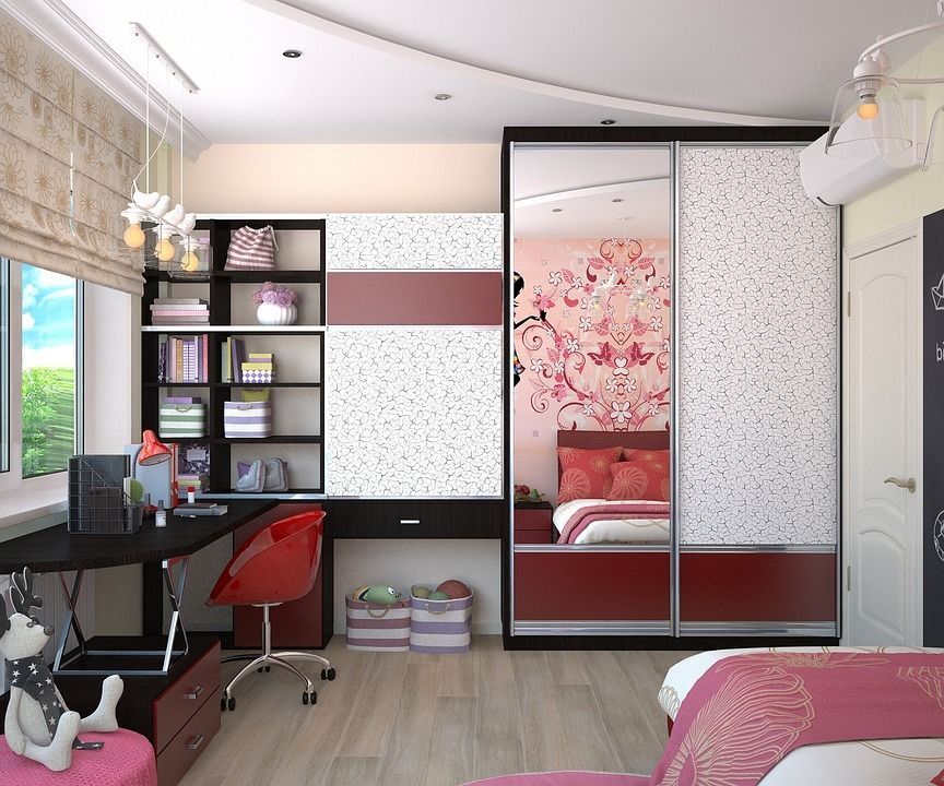 Un dormitorio con cama, escritorio, silla y puertas corredizas de vidrio.