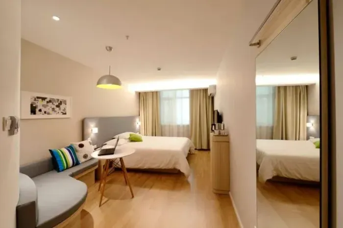 Una habitación de hotel con dos camas, un sofá, una mesa y un espejo.