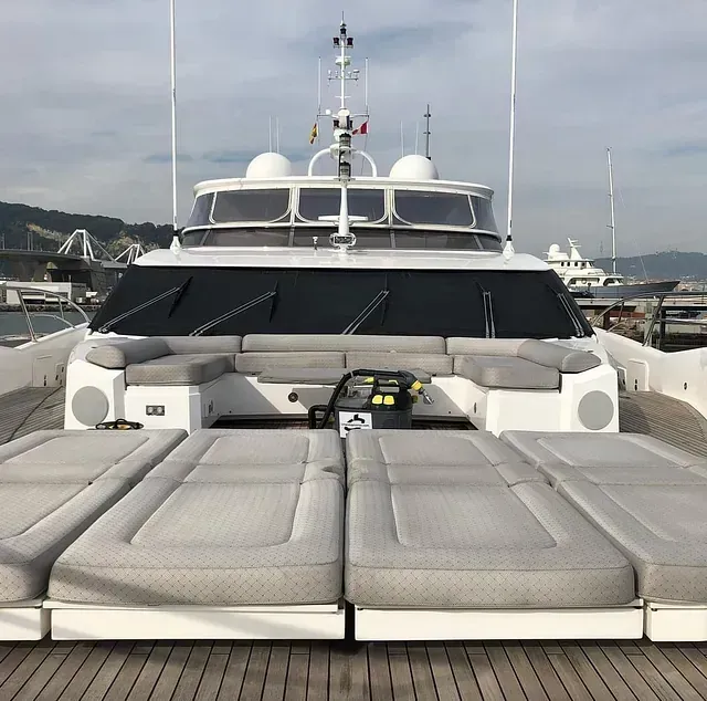 Tumbonas y bancos en la cubierta de un yate blanco atracado en un puerto deportivo.