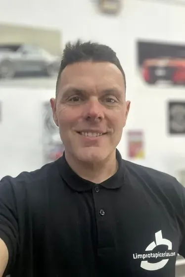 Un hombre con un polo negro se está tomando un selfie.