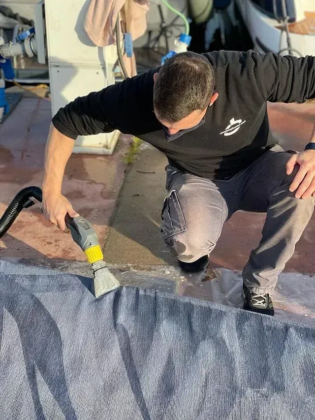 Un hombre está limpiando una alfombra con una aspiradora.