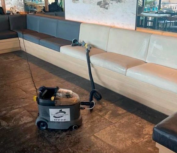 Una máquina de limpieza comercial al lado de una cabina larga y acolchada en un restaurante.