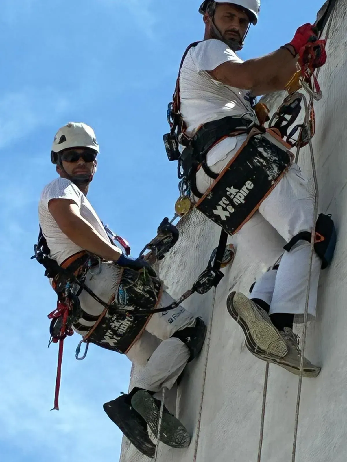 Dos personas con equipo de seguridad descendiendo en rápel por una pared.