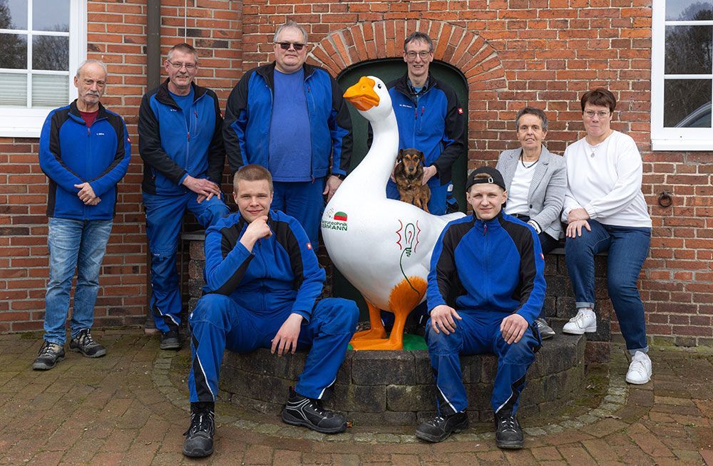 Eine Gruppe von Menschen posiert für ein Foto mit einer Gänsestatue.