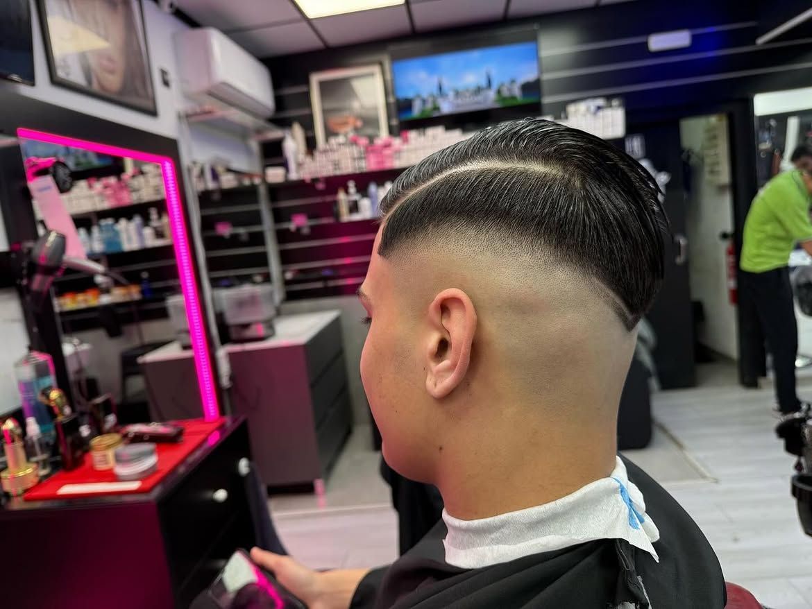 Persona sentada en una silla de barbería con un degradado recién hecho, vista desde atrás.