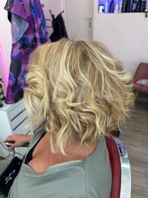 Corte bob rubio y ondulado, visto desde atrás en una silla de peluquería