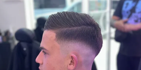 Primer plano de un corte degradado corto en una barbería, de perfil