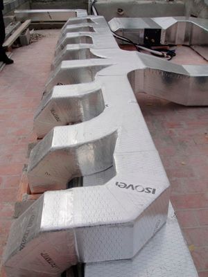 Una fila de conductos de aluminio colocados encima de una mesa de madera.
