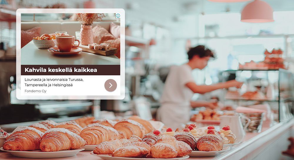 Etualalla leipomon tiski, täynnä croissanteja, ja sen päällä kahvimainos.