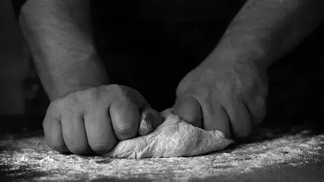 Una persona está amasando masa sobre una mesa en una fotografía en blanco y negro.
