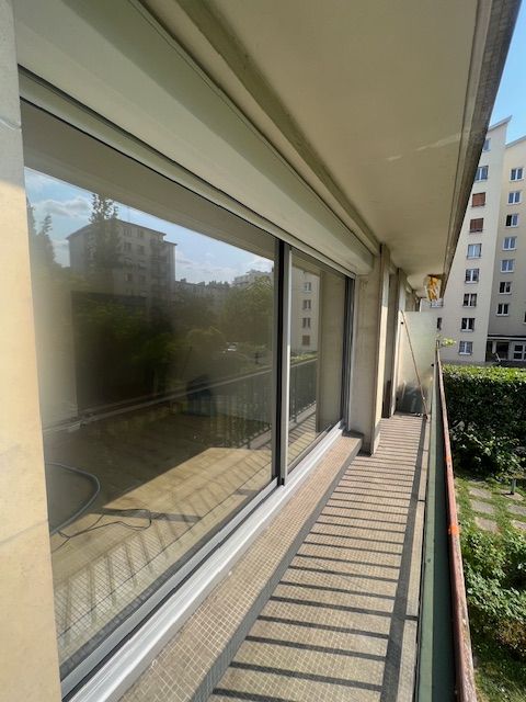 Passerelle avec balcon et rambarde en verre, ombres rayées baignées de soleil et immeubles d'appartements au-delà