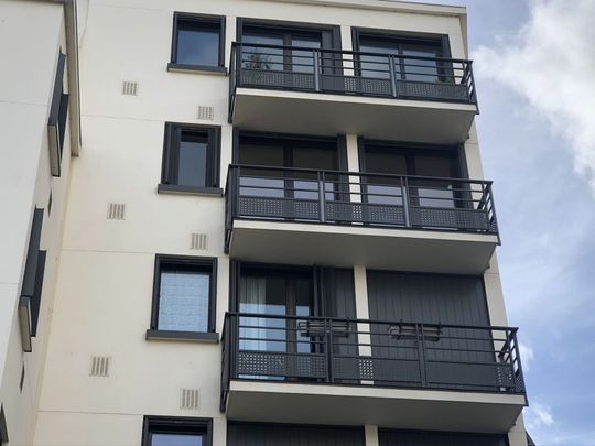 L'extérieur d'un immeuble d'appartements blanc, avec ses balcons superposés aux balustrades.