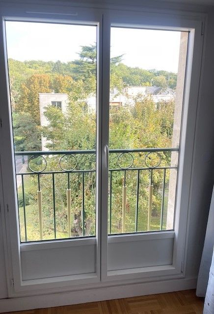 Portes-fenêtres blanches donnant sur des arbres verdoyants et des maisons à l'extérieur