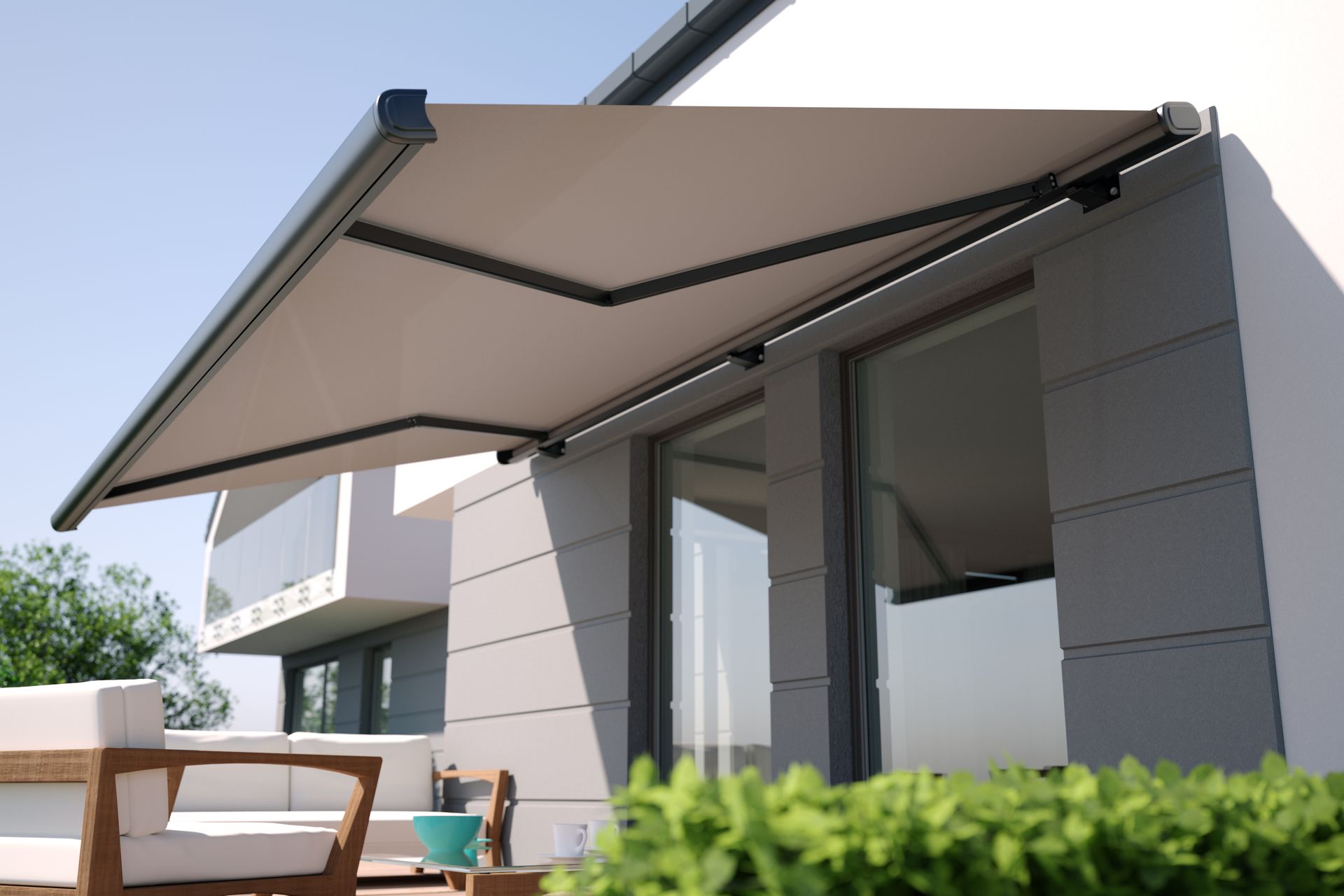 Un auvent de terrasse rétractable beige s'étend au-dessus de la façade d'une maison.