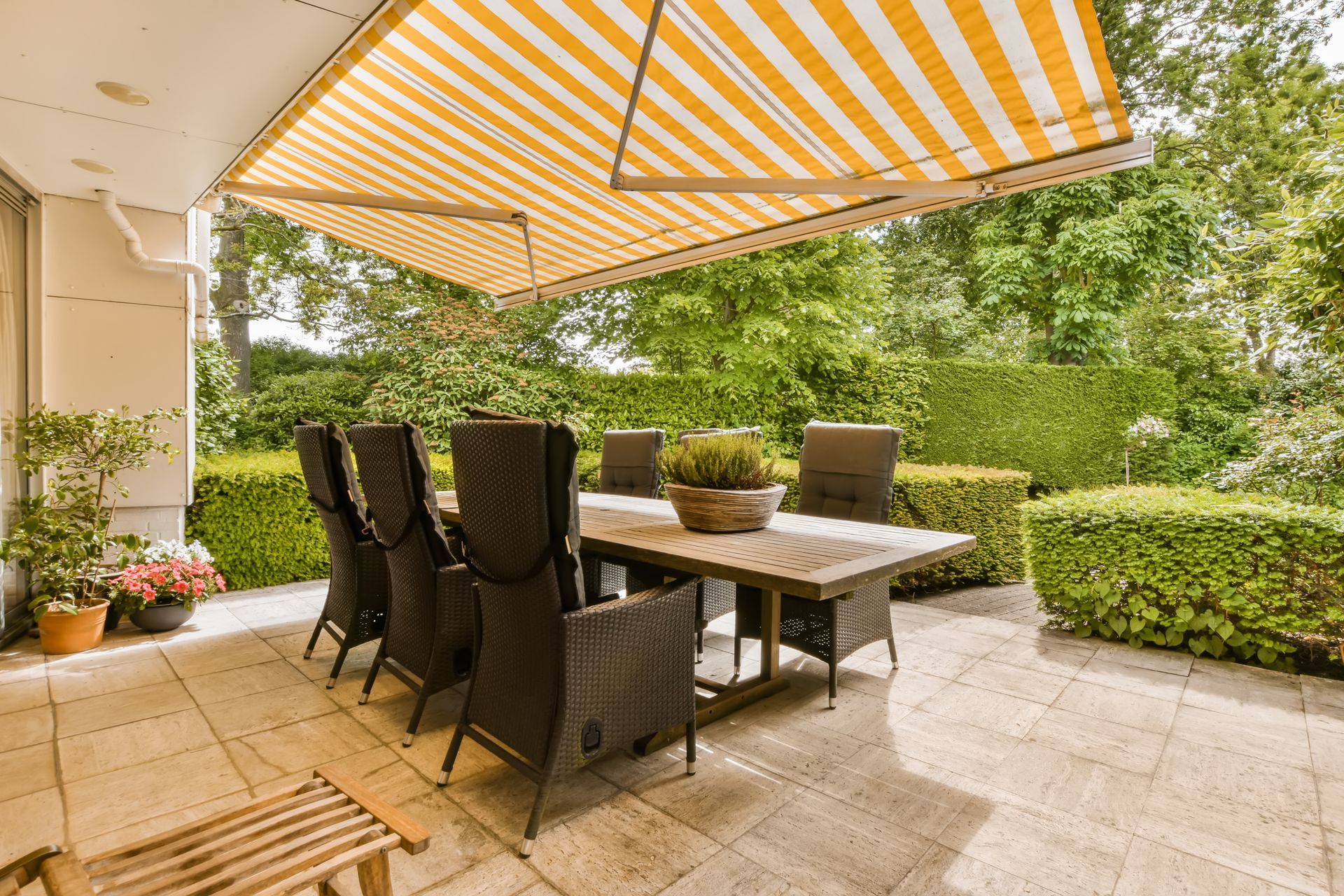 Terrasse avec une table à manger en bois et des chaises foncées.