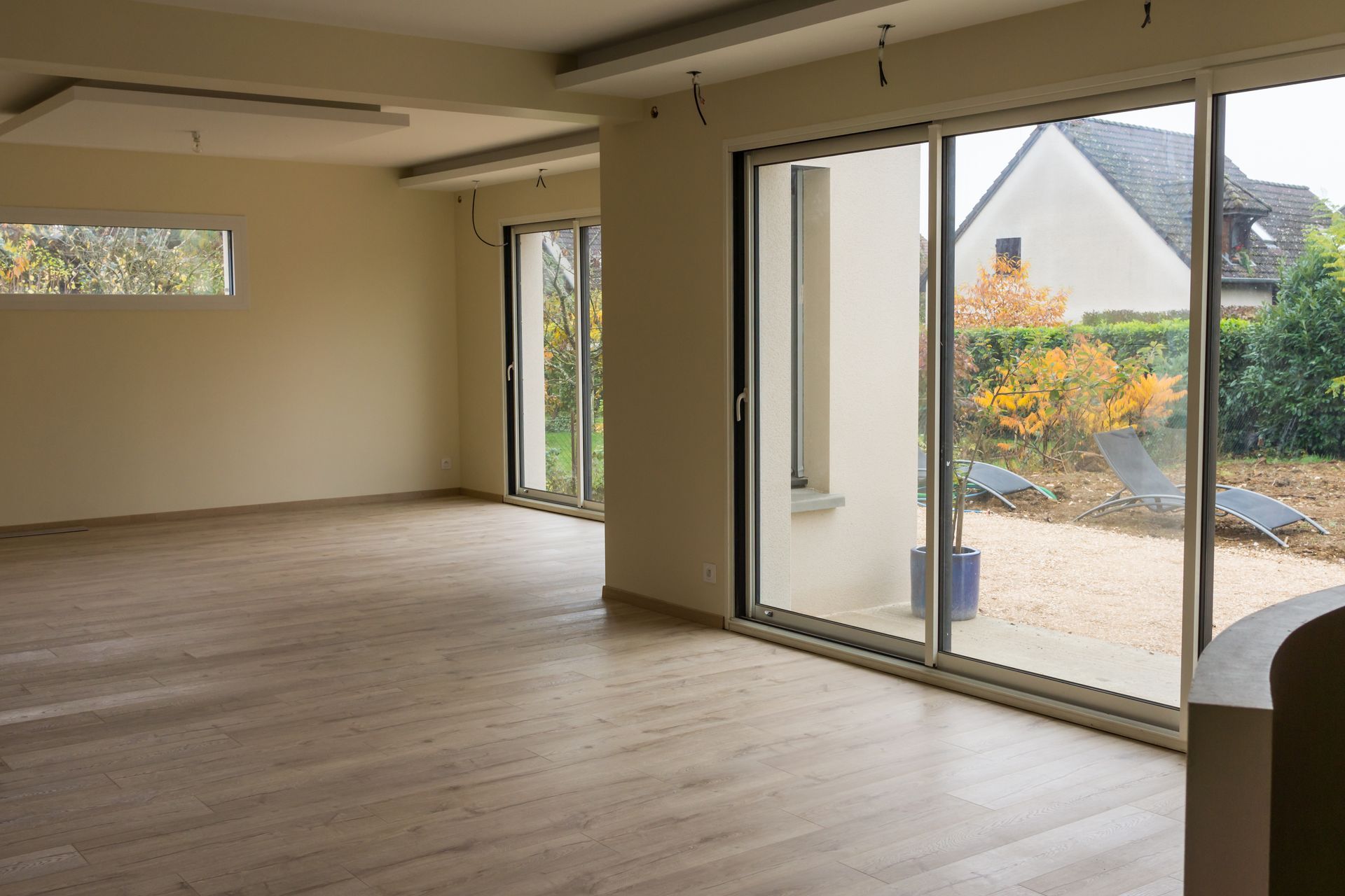 Une pièce spacieuse et moderne avec parquet clair et murs couleur crème, dotée de grandes portes coulissantes.