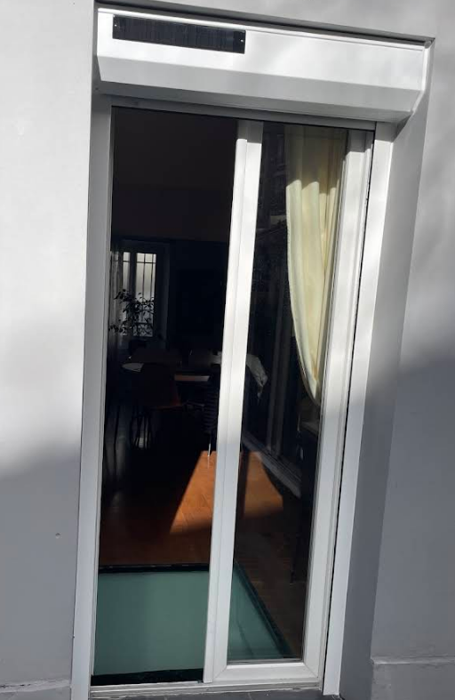 Une porte coulissante à cadre blanc, partiellement ouverte, laisse entrevoir une pièce intérieure.