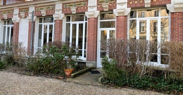 Façade de maison de ville en briques avec fenêtres à cadre blanc, portes-fenêtres doubles.