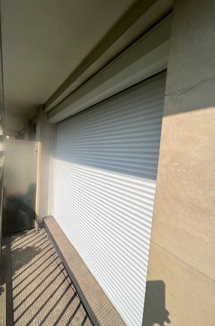 Un large volet roulant sur un balcon.