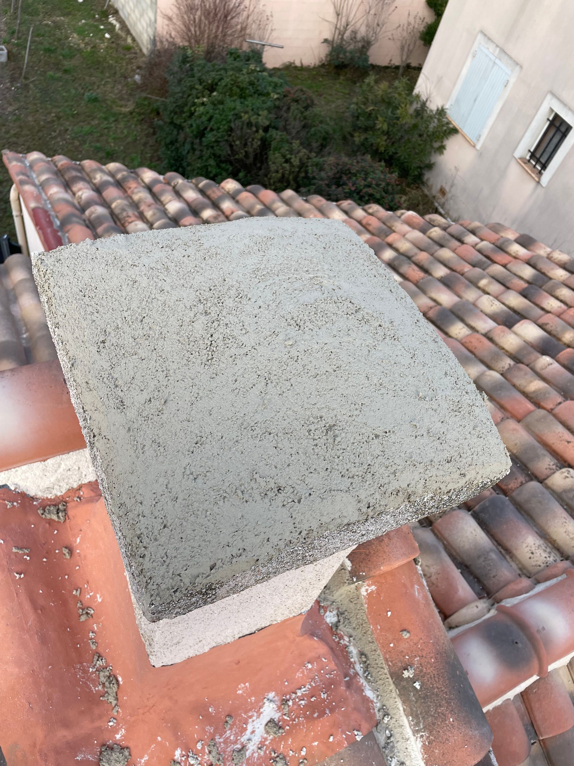 Couverture de cheminée en béton sur toit en tuiles