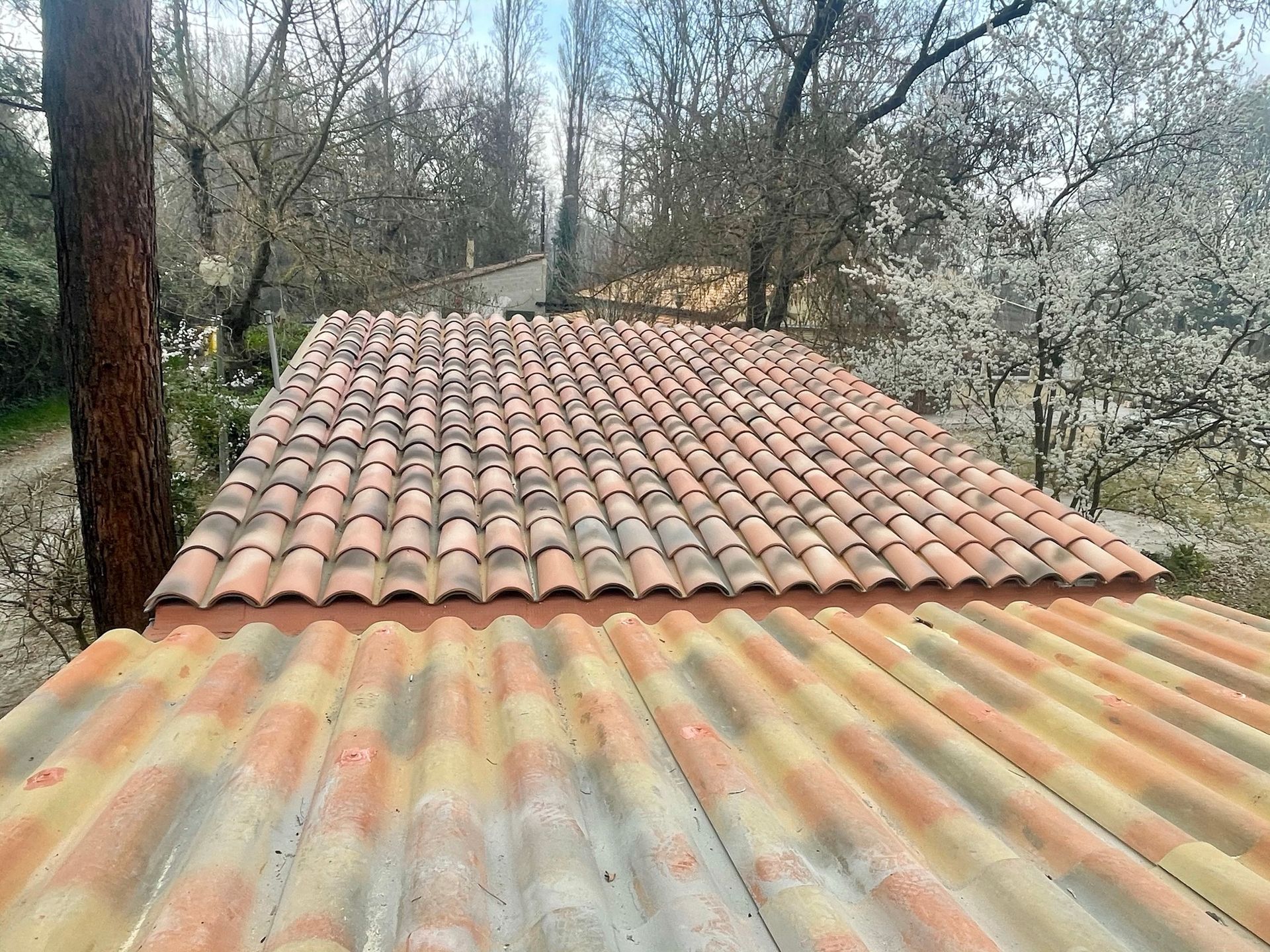 Vue d'un double toit rénové, une partie en tuiles l'autre en plaques ondulées